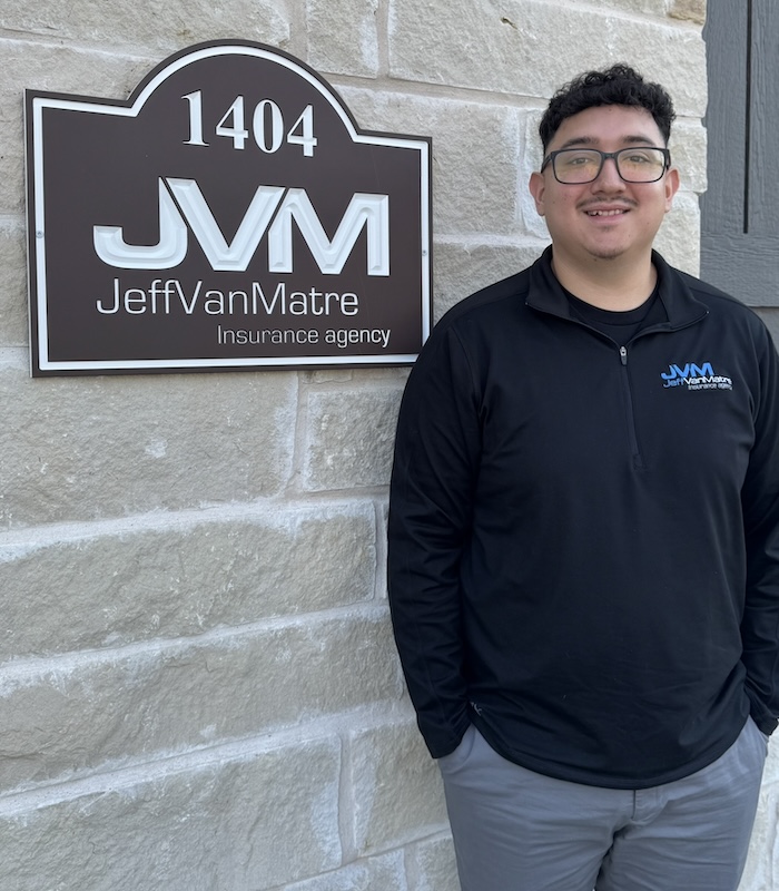 About - Jeff Van Matre Insurance Agency Team Standing and Posing in Front of the Agency Logo